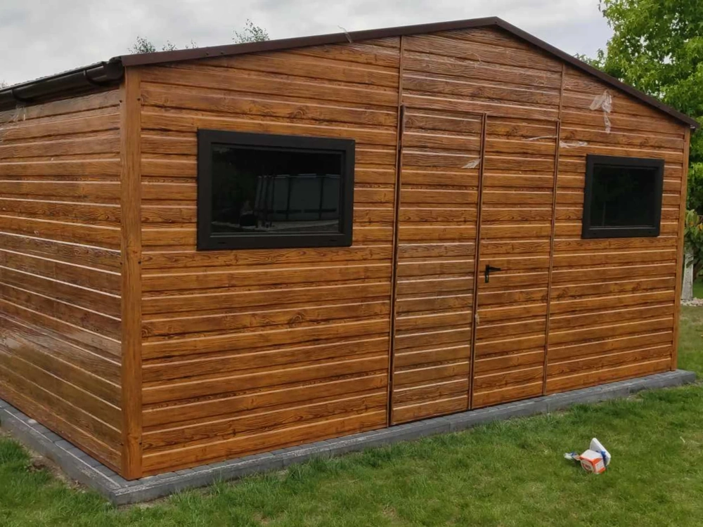 Domek narzędziowy z drewnopodobnym wykończeniem i dwoma oknami osadzony na trawniku
