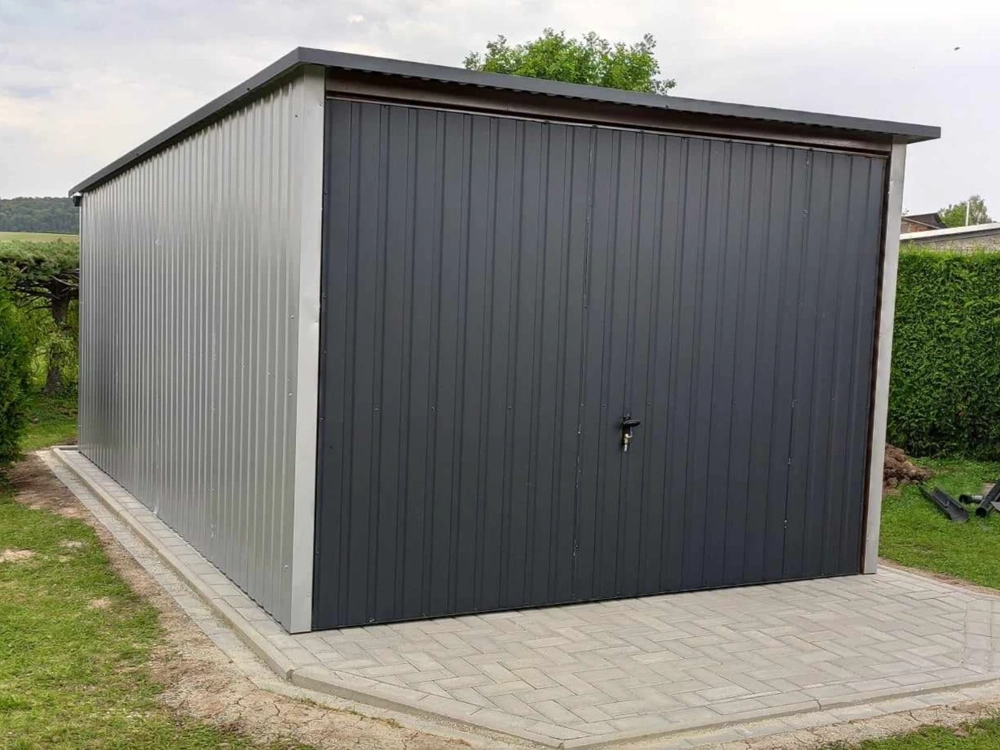 Garaż blaszany z ciemnoszarymi panelami na podjeździe z kostki brukowej