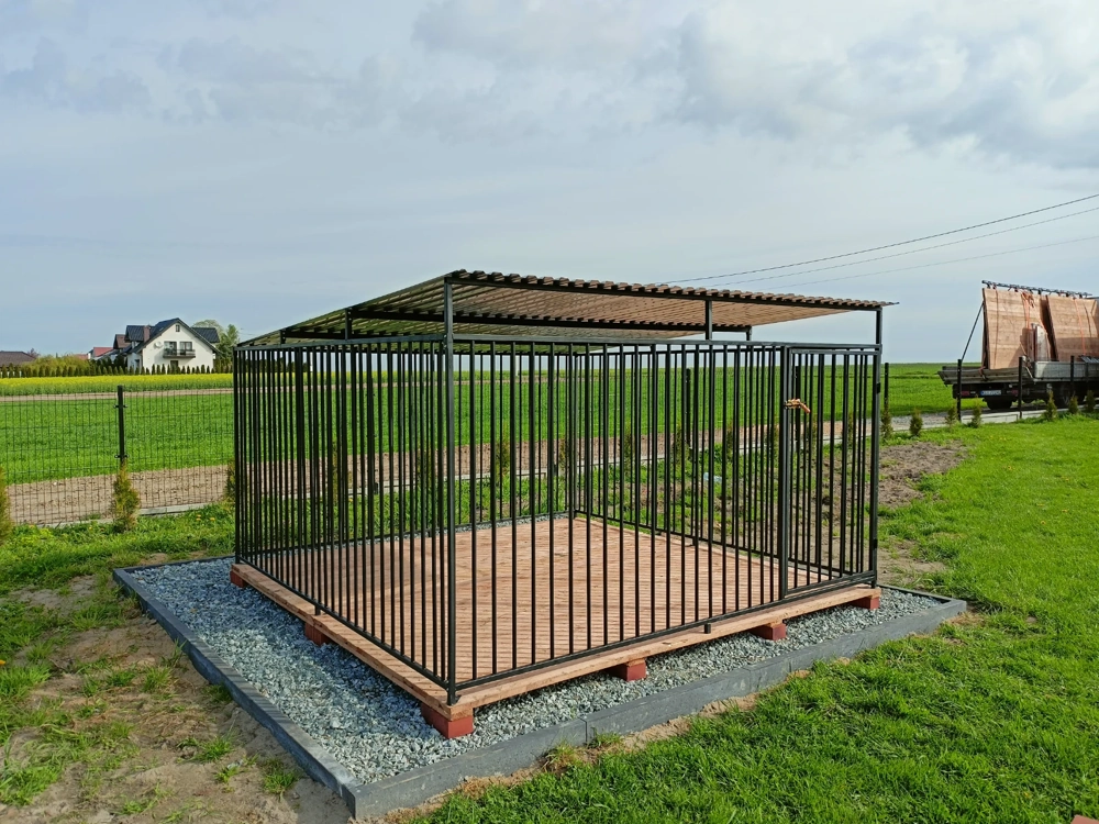 Stalowy kojec dla psów z zadaszeniem i drewnianą podłogą na przygotowanym podłożu