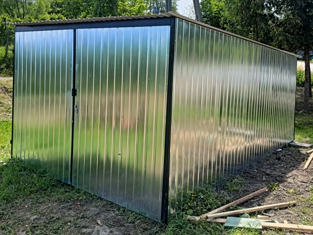 Garaż blaszany z ocynkowanych paneli stalowych na trawiastym podłożu