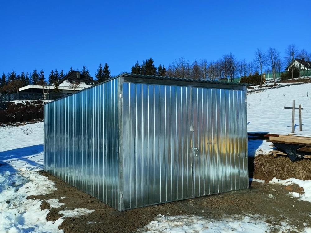 Garaż blaszany na przygotowanym podłożu w śnieżnym otoczeniu, widok bokiem