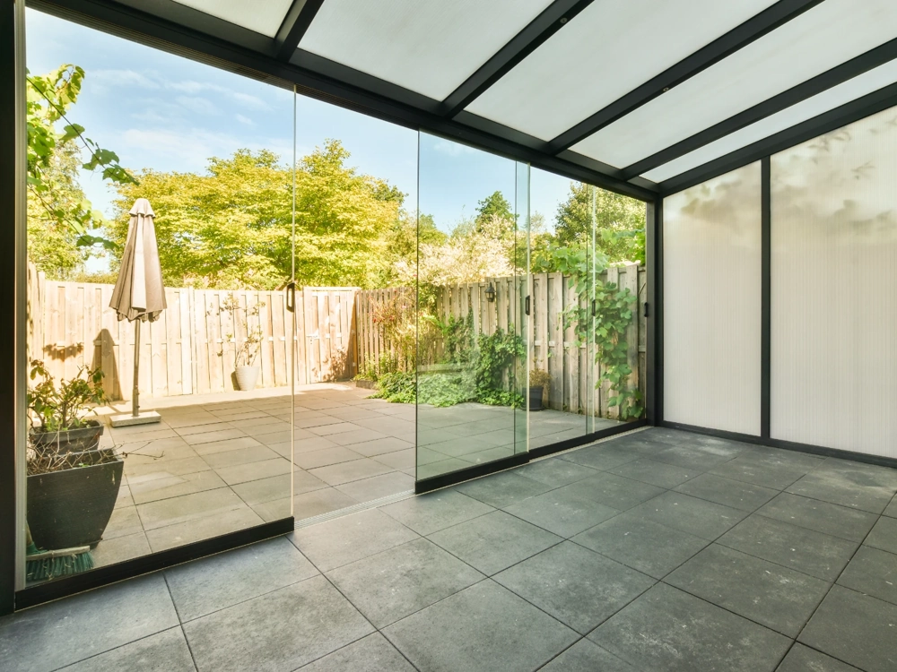 Ogrody zimowe – oszklona weranda ze stalową konstrukcją i przesuwnymi szklanymi drzwiami